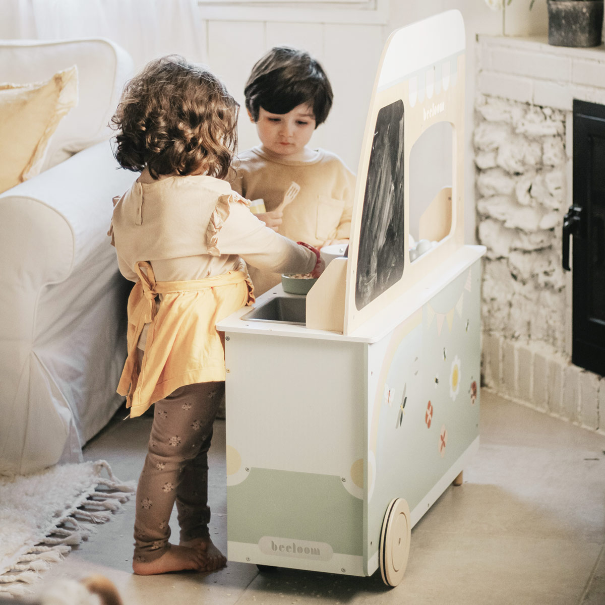 Niño y niña jugando juntos a cocinitas en el salón de casa