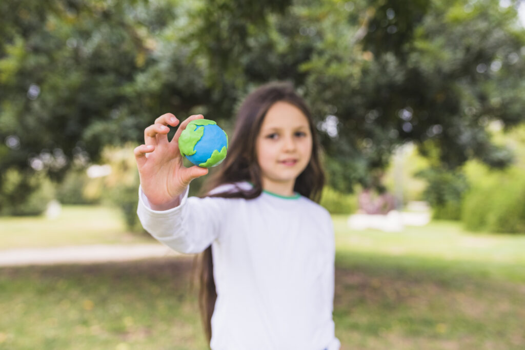 Niña con el planeta Tierra, hecho con plastilina, en sus manos