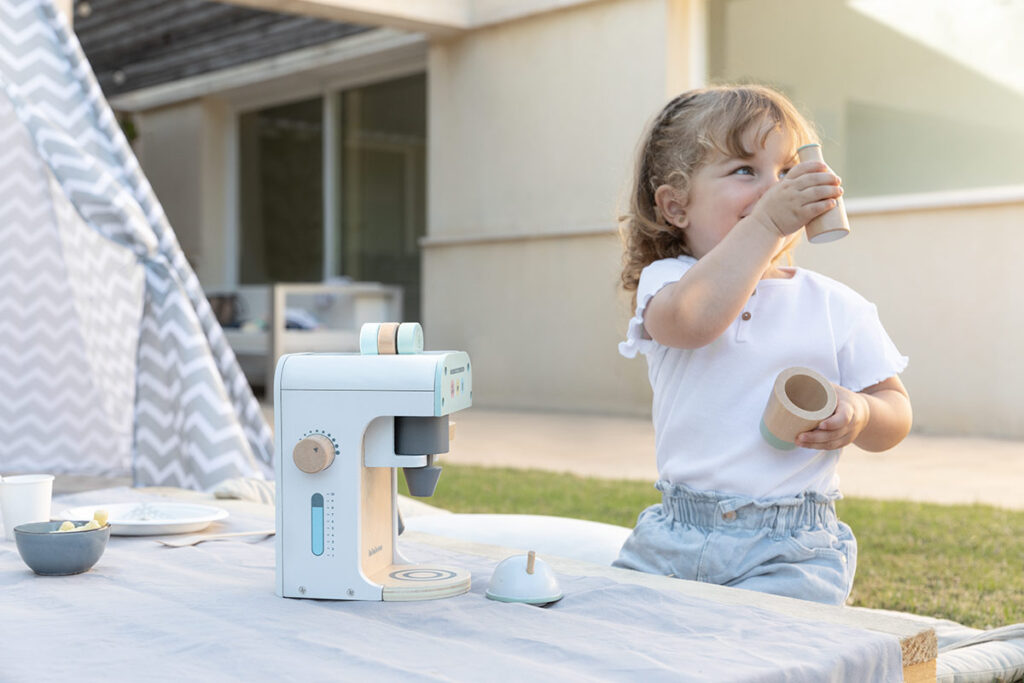 Niña jugando a un juego de imitación con cafetera de juguete